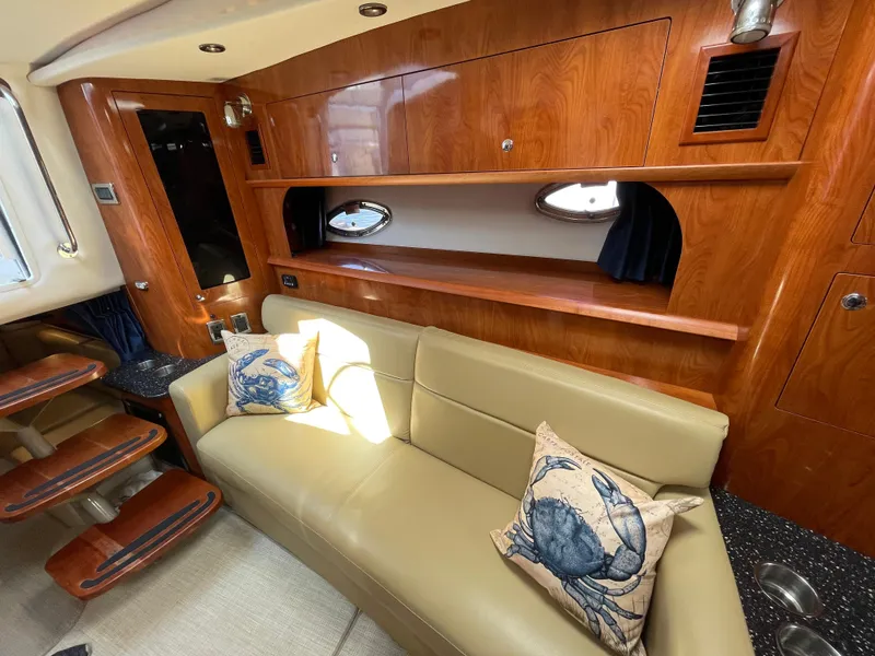 Slide: The Image of 2008 Four Winns V338 yacht interior with beige leather sofa and nautical-themed pillows. - 16