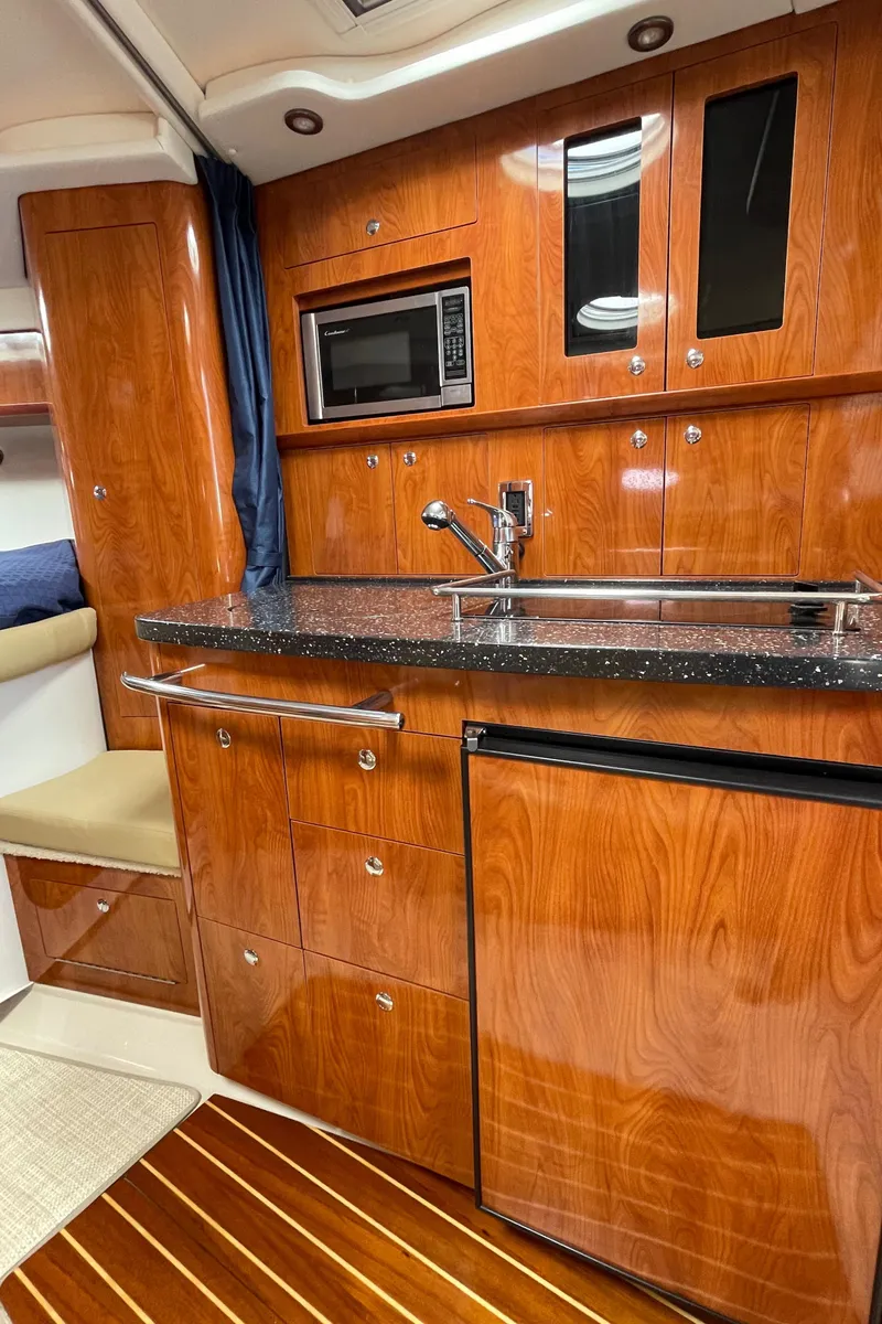 Slide: The Image of 2008 Four Winns V338 yacht interior kitchen with wood cabinetry, microwave, sink, and mini-fridge. - 20
