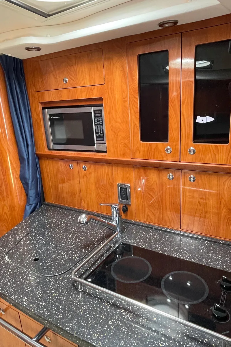 Slide: The Image of 2008 Four Winns V338 yacht kitchen with microwave, stove, and wooden cabinetry. - 21