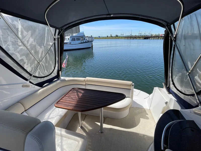 Slide: The Image of 2008 Four Winns V338 boat interior with seating and table, docked by the water. - 4