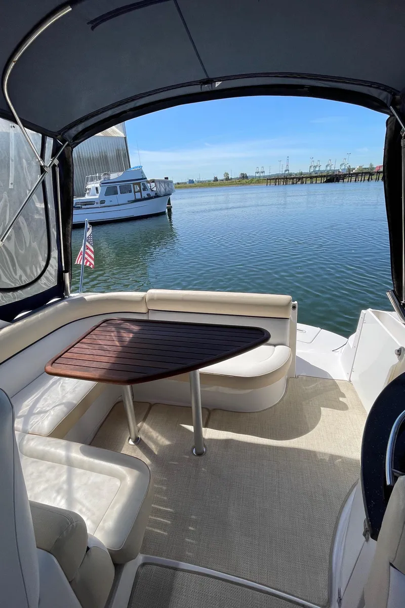 Slide: The Image of 2008 Four Winns V338 boat interior with seating and table, docked by the water. - 7