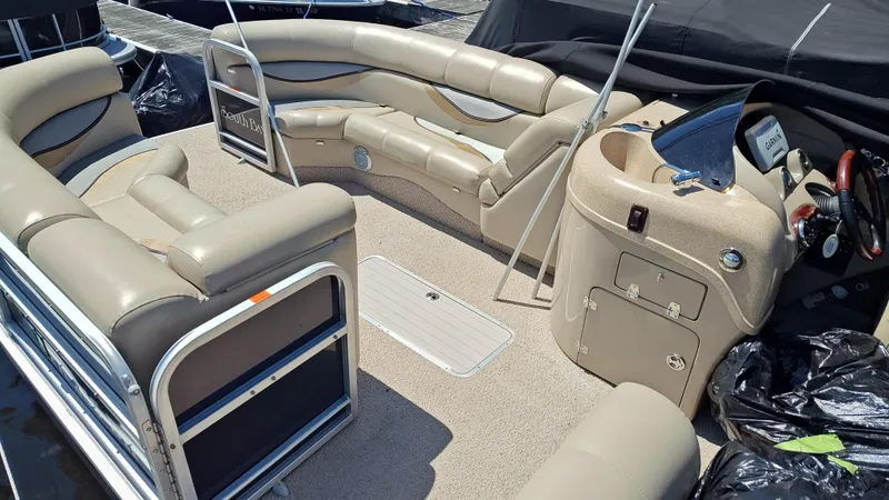Slide: The Image of 2011 South Bay 722CR pontoon boat interior with beige seating and steering console. - 4