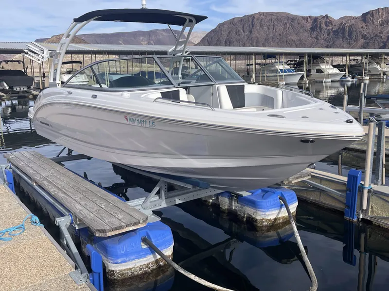 Slide: The Image of 2022 Chaparral 23 Surf boat docked at a marina with scenic mountain backdrop. - 16