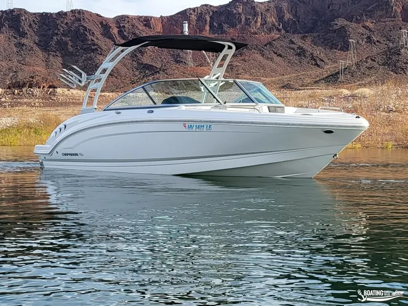 Slide: The Image of 2022 Chaparral 23 Surf boat on calm water with rocky background. - 2