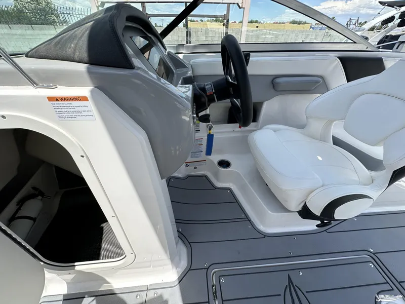 Slide: The Image of 2022 Chaparral 23 Surf boat interior with white captain's chair and steering wheel. - 20