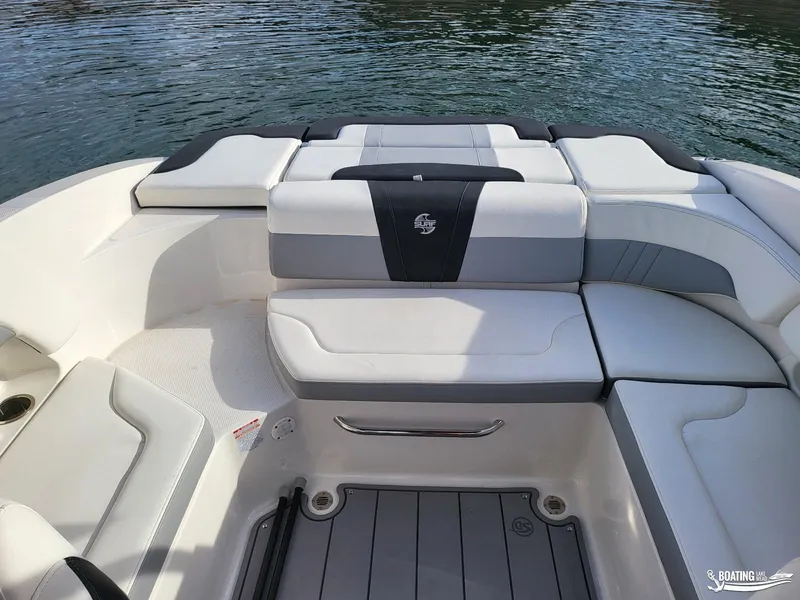 Slide: The Image of 2022 Chaparral 23 Surf boat interior with cushioned seating and water backdrop. - 23