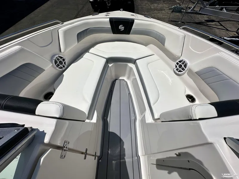 Slide: The Image of 2022 Chaparral 23 Surf boat interior with white cushioned seating and built-in speakers. - 24