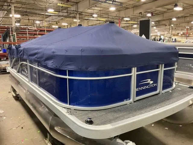 Slide: The Image of 2025 Bennington 188 SVL pontoon boat with blue cover in a warehouse setting. - 21