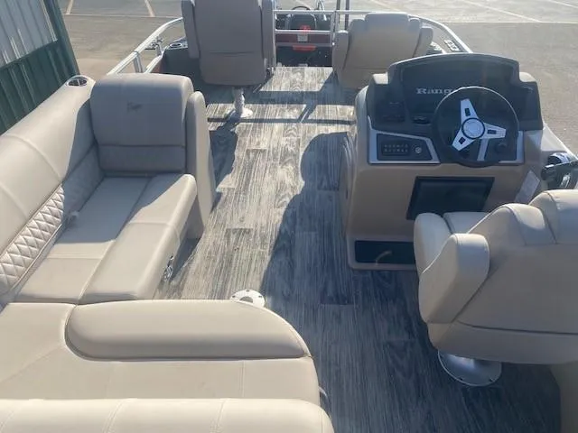 Slide: The Image of 2024 Ranger Reata 220F pontoon boat interior with beige seating and modern dashboard. - 4