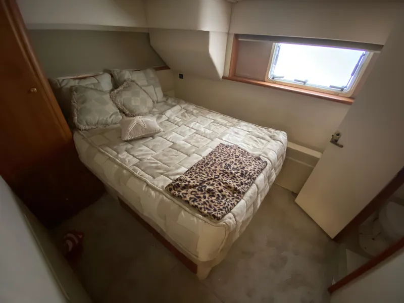 Slide: The Image of Cozy bedroom in a 1999 Silverton 392 Motor Yacht with a window and plush bedding. - 22
