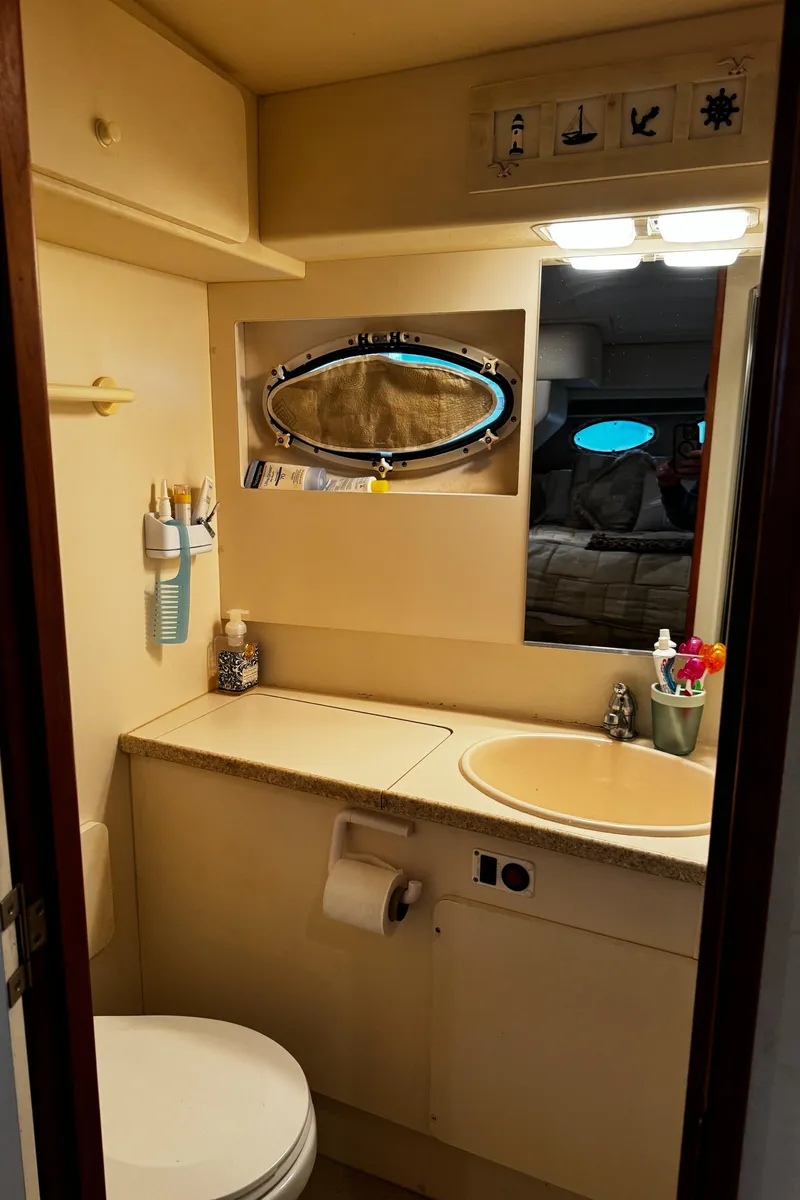 Slide: The Image of 1999 Silverton 392 Motor Yacht bathroom with sink, toilet, and porthole window. - 24