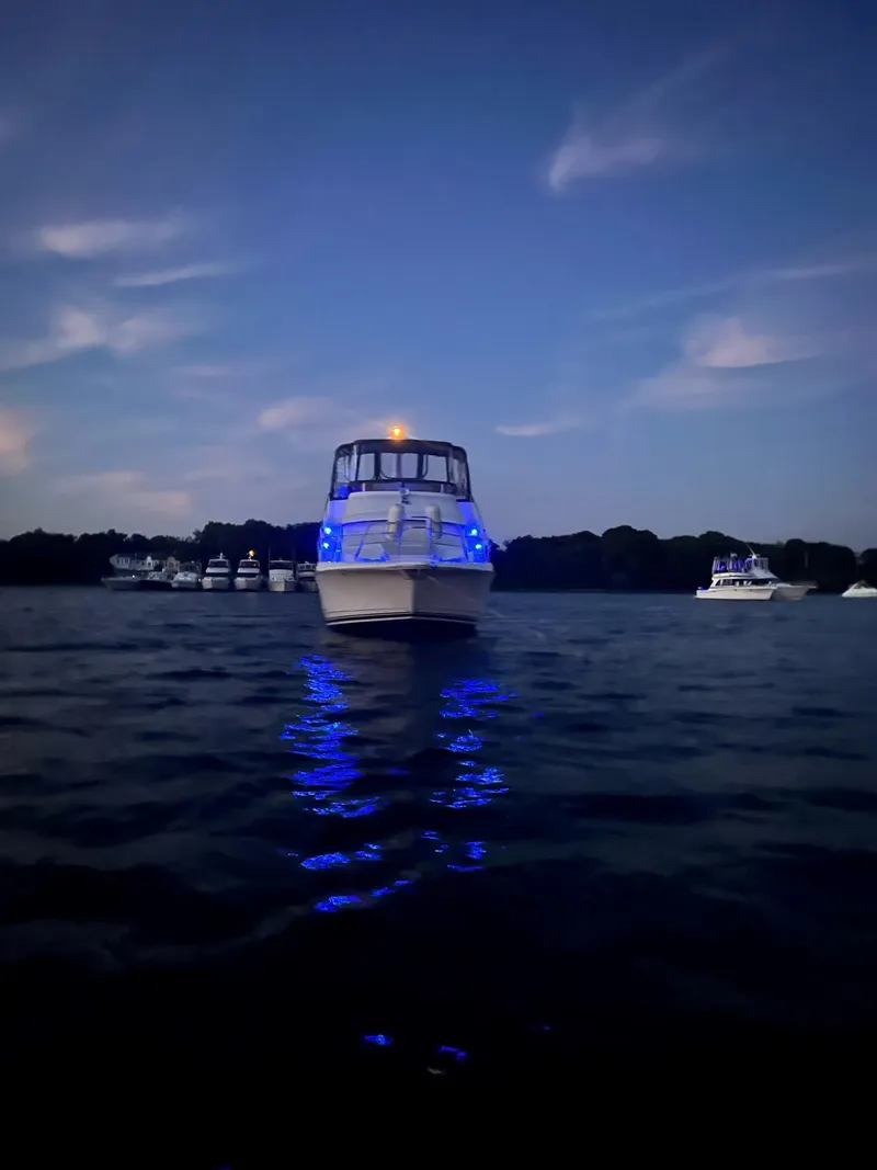 Slide: The Image of 1999 Silverton 392 Motor Yacht illuminated with blue lights on a calm evening. - 38