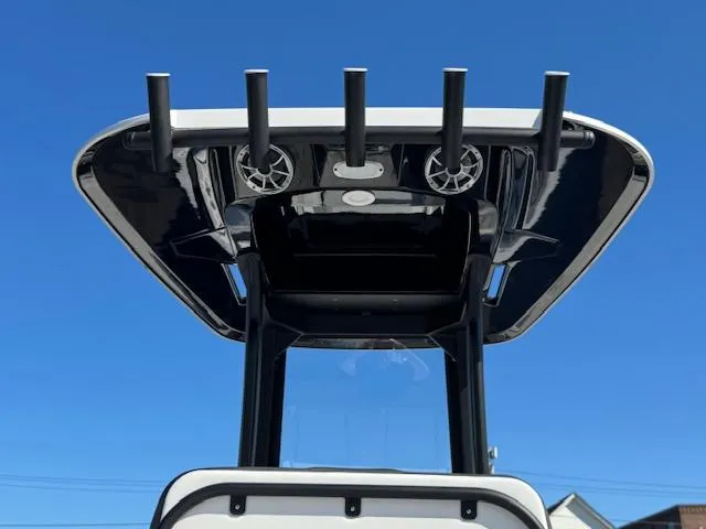 Slide: The Image of 2024 Yamaha Boats 255 FSH Sport H T-top with rod holders and speakers against blue sky. - 19