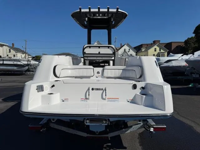 Slide: The Image of 2024 Yamaha Boats 255 FSH Sport H, rear view, white exterior, parked outdoors. - 2