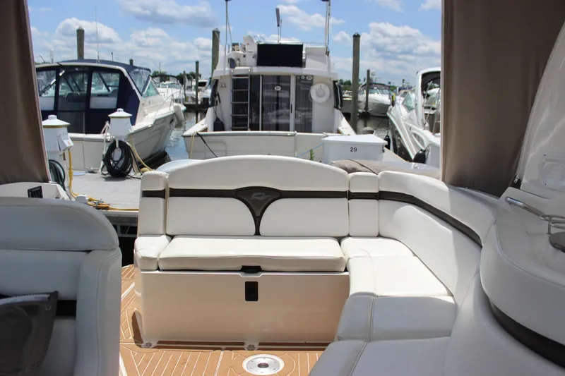 Slide: The Image of 2013 Rinker 31 boat interior with white seating at a marina. - 24
