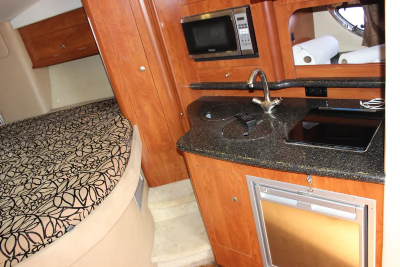 Slide: The Image of 2013 Rinker 31 boat interior with kitchenette and bed. - 27