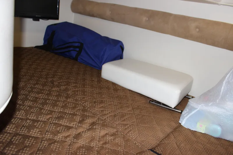Slide: The Image of Interior cabin of a 2013 Rinker 31 boat with brown quilted bedding. - 35