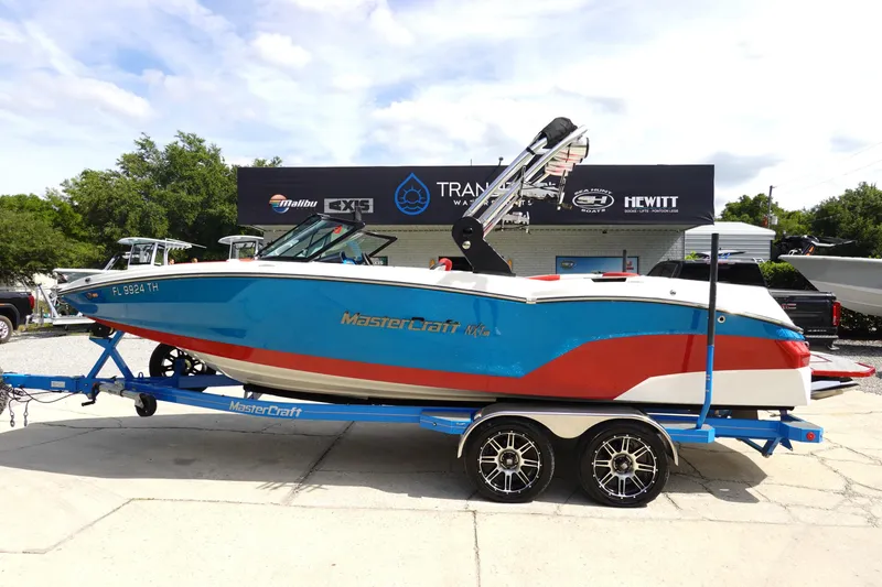 Slide: The Image of 2021 MasterCraft NXT22 boat on a trailer, blue and red color scheme. - 0