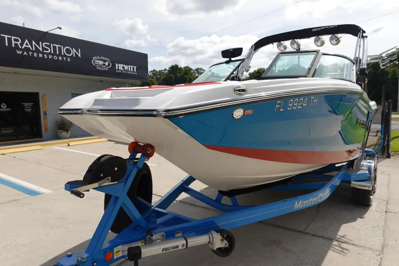 Slide: The Image of 2021 MasterCraft NXT22 boat on a blue trailer at Transition Watersports. - 2