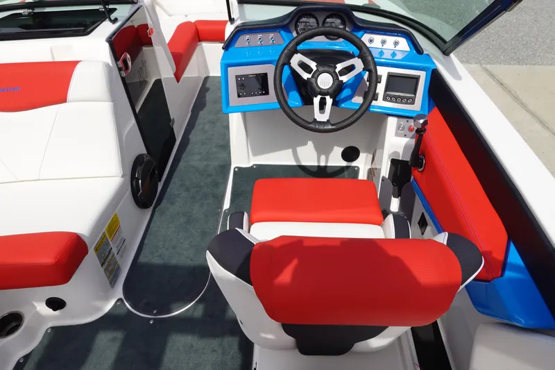 Slide: The Image of 2021 MasterCraft NXT22 boat interior with red and white seating, blue dashboard, and steering wheel. - 23
