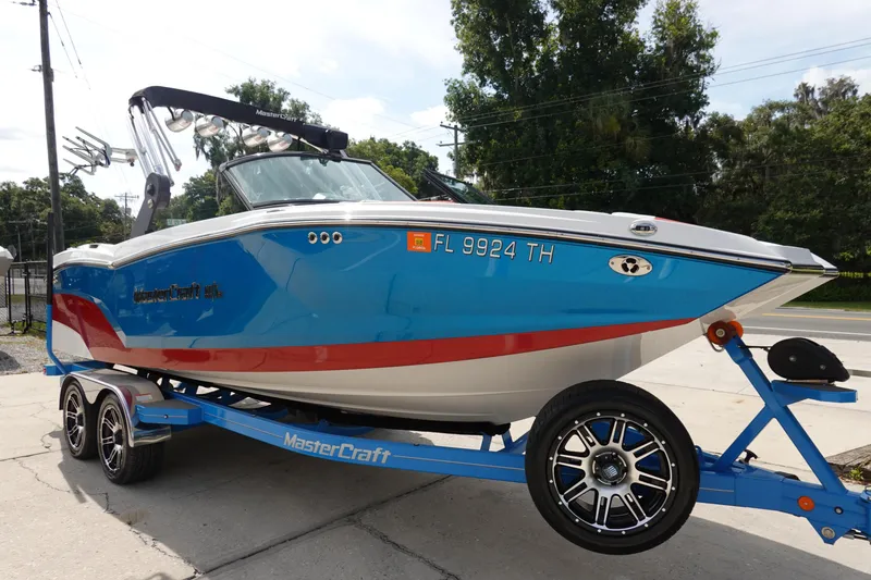 Slide: The Image of 2021 MasterCraft NXT22 boat on a trailer, blue and white with red accents. - 3