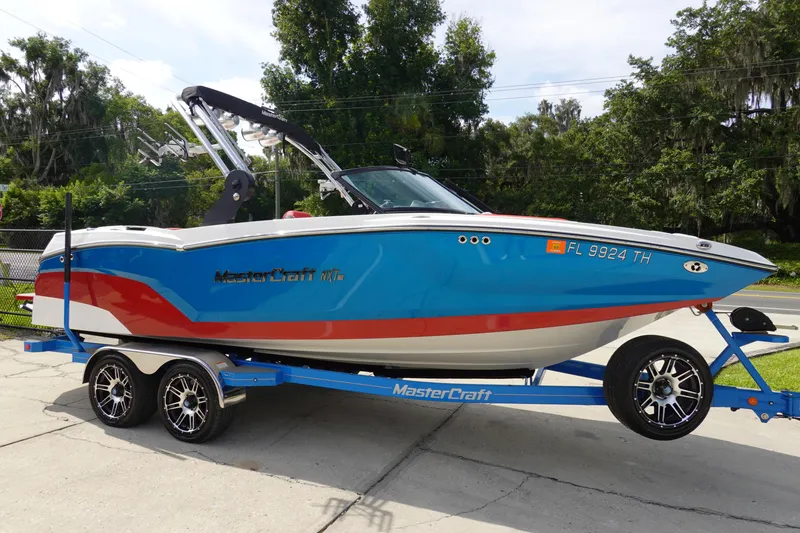 Slide: The Image of 2021 MasterCraft NXT22 boat on a trailer, blue and white with red accents. - 4
