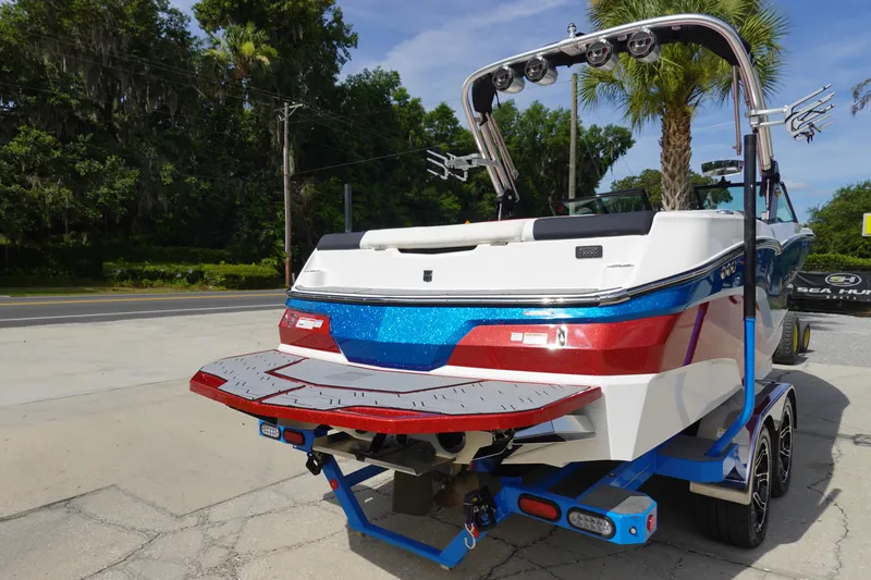 Slide: The Image of 2021 MasterCraft NXT22 boat on trailer, rear view with vibrant blue and red accents. - 7