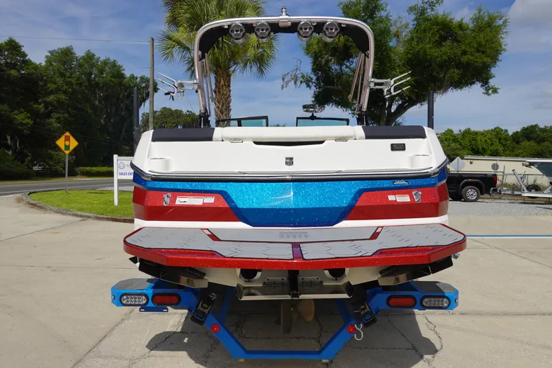 Slide: The Image of 2021 MasterCraft NXT22 boat, rear view, red and blue color scheme, parked outdoors. - 9