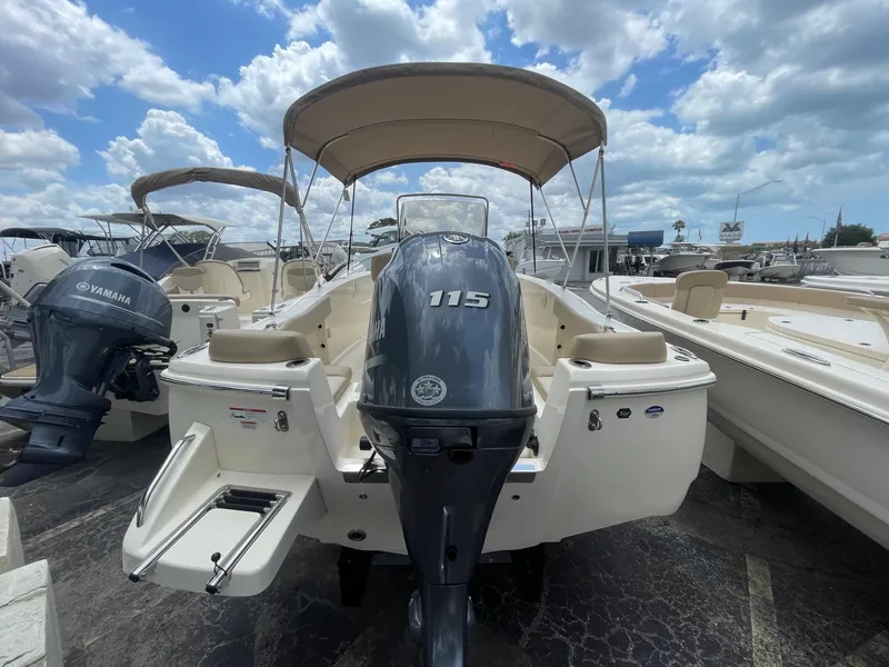 Slide: The Image of 2024 Scout 195 Sportfish boat with Yamaha 115 engine, docked under a cloudy sky. - 2