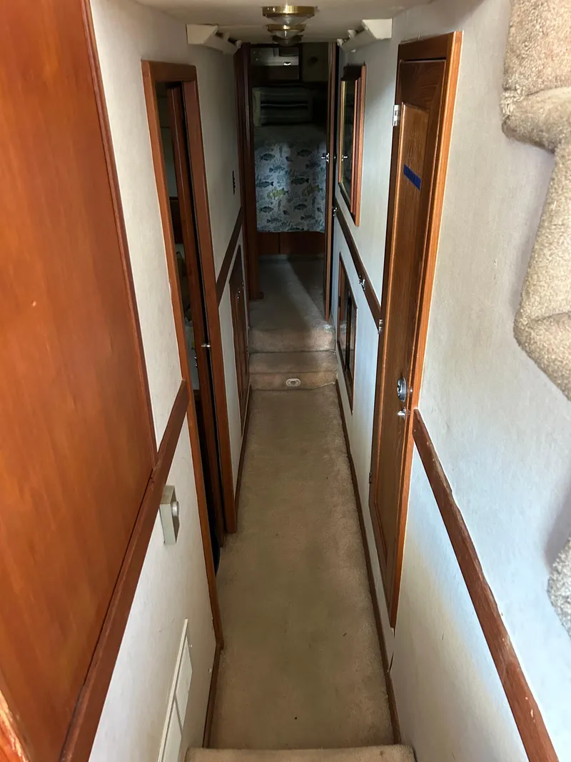 Slide: The Image of Narrow hallway inside a 1994 Bayliner 4788 yacht with wooden trim and carpeted floor. - 16