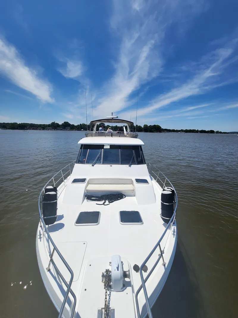 Slide: The Image of 1994 Bayliner 4788 yacht on calm water under a clear blue sky. - 26