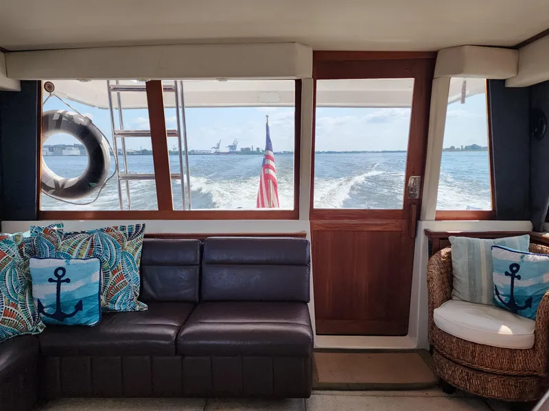Slide: The Image of Interior of 1994 Bayliner 4788 yacht with ocean view, featuring nautical-themed cushions. - 27