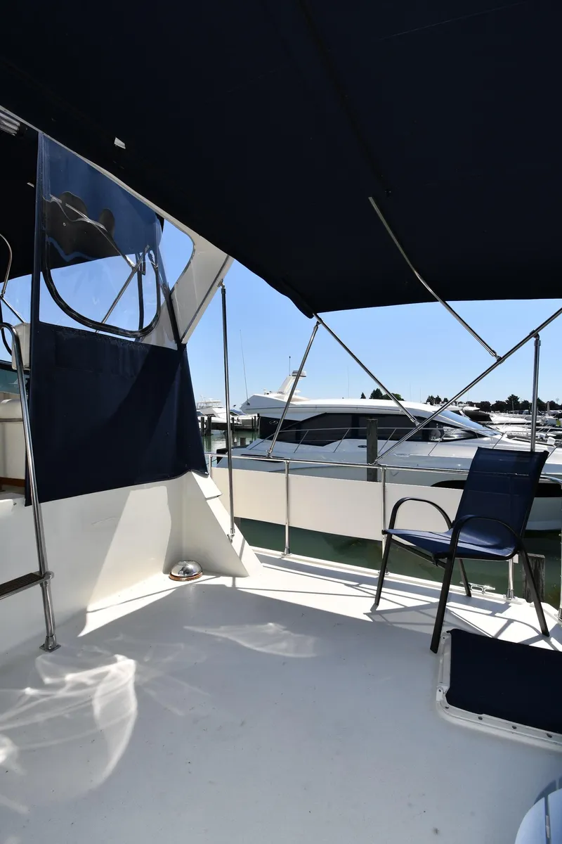 Slide: The Image of 1988 Tollycraft 34 Sundeck yacht with shaded seating area and marina view. - 8