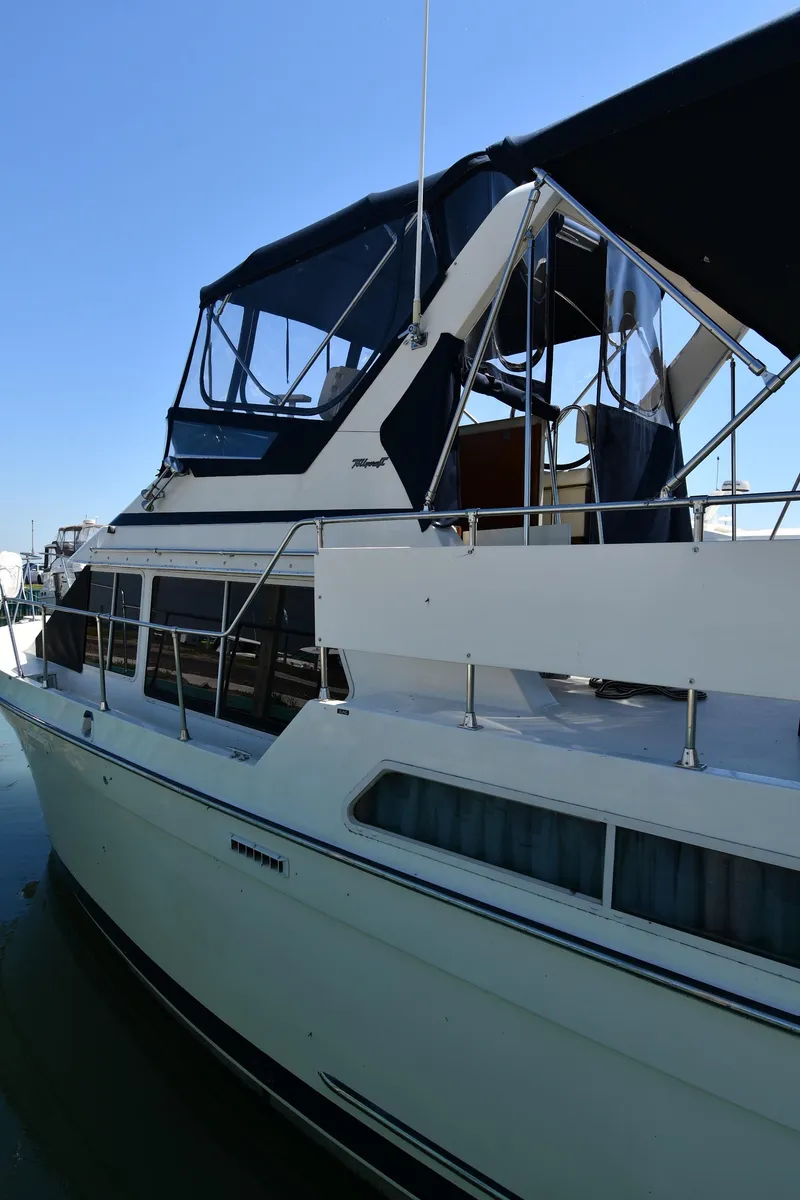 Slide: The Image of 1988 Tollycraft 34 Sundeck yacht with blue canopy docked in marina. - 2