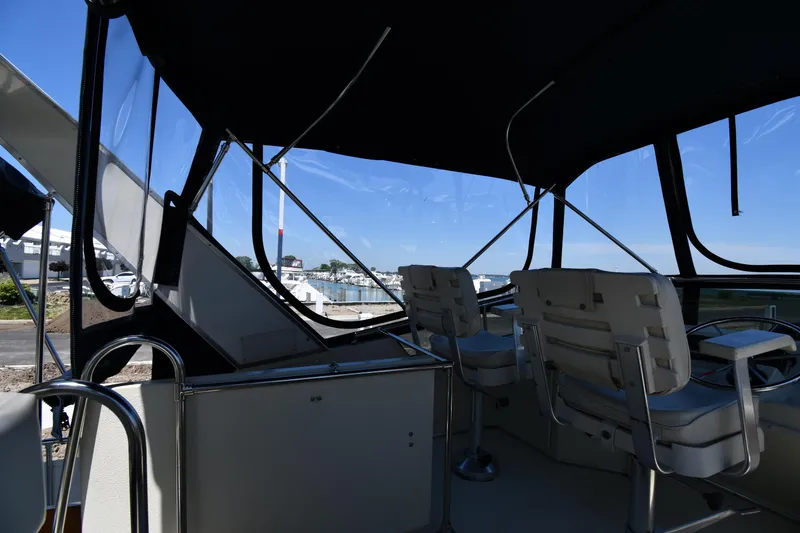 Slide: The Image of 1988 Tollycraft 34 Sundeck boat interior with helm chairs and clear canopy. - 23