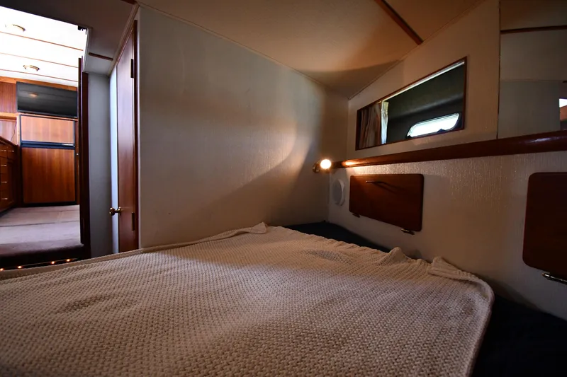 Slide: The Image of 1988 Tollycraft 34 Sundeck interior cabin with bed and wooden accents. - 32