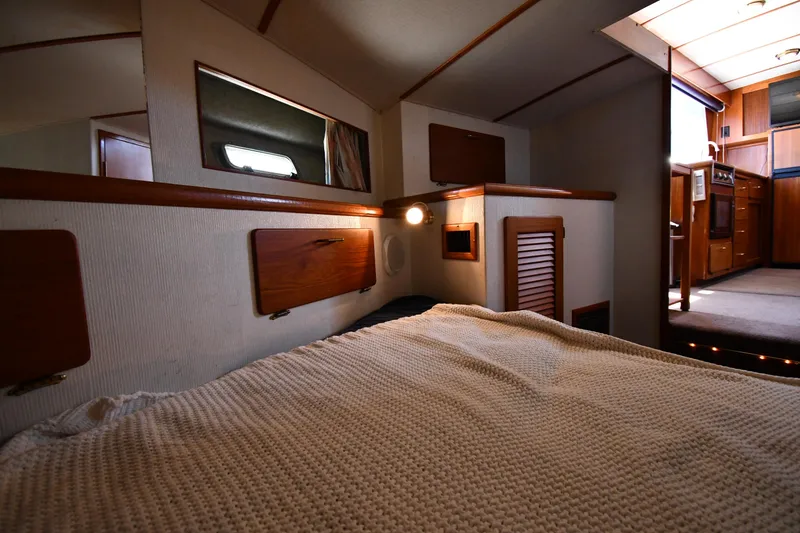 Slide: The Image of 1988 Tollycraft 34 Sundeck interior cabin with bed, wooden accents, and lighting. - 33