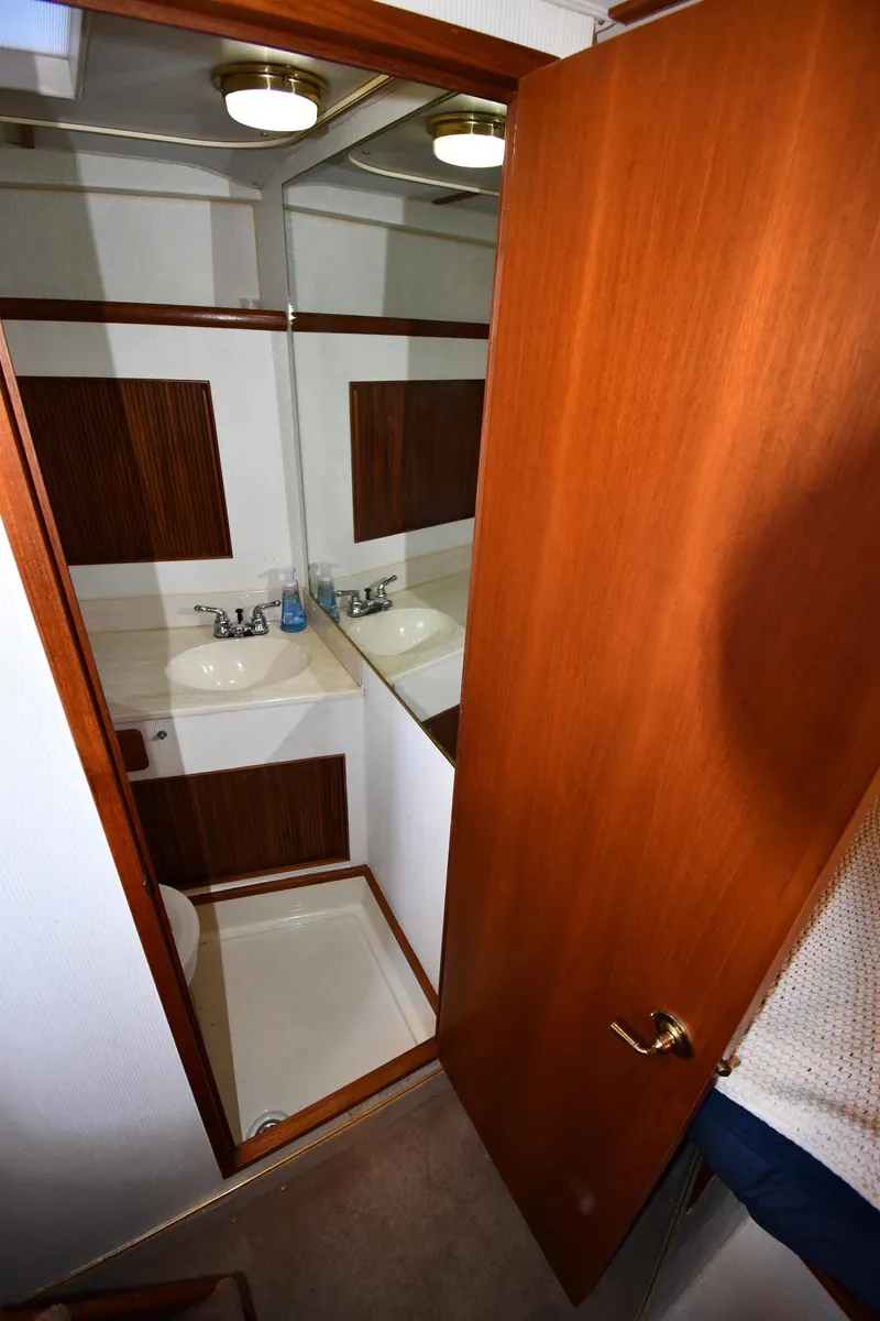 Slide: The Image of 1988 Tollycraft 34 Sundeck bathroom with sink, mirror, and wooden door. - 34