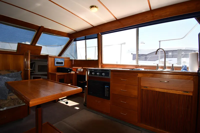 Slide: The Image of 1988 Tollycraft 34 Sundeck interior with kitchen, dining table, and large windows. - 36