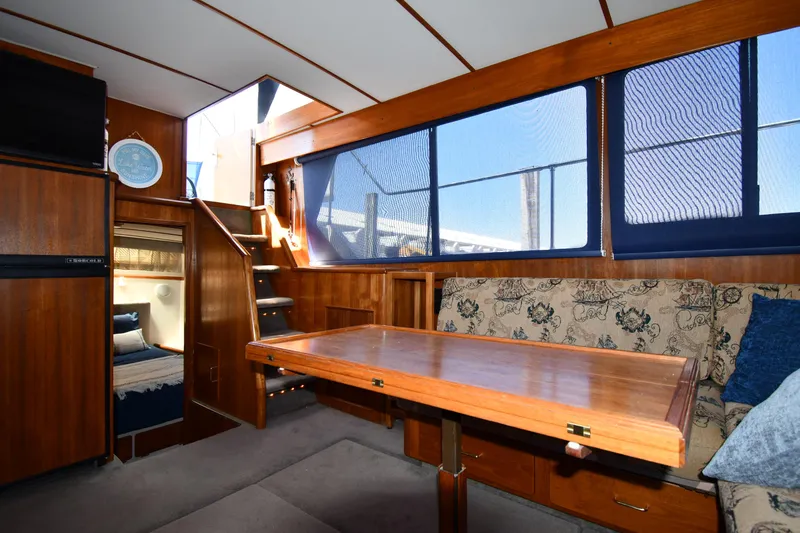 Slide: The Image of 1988 Tollycraft 34 Sundeck interior with wooden table, sofa, and large windows. - 40
