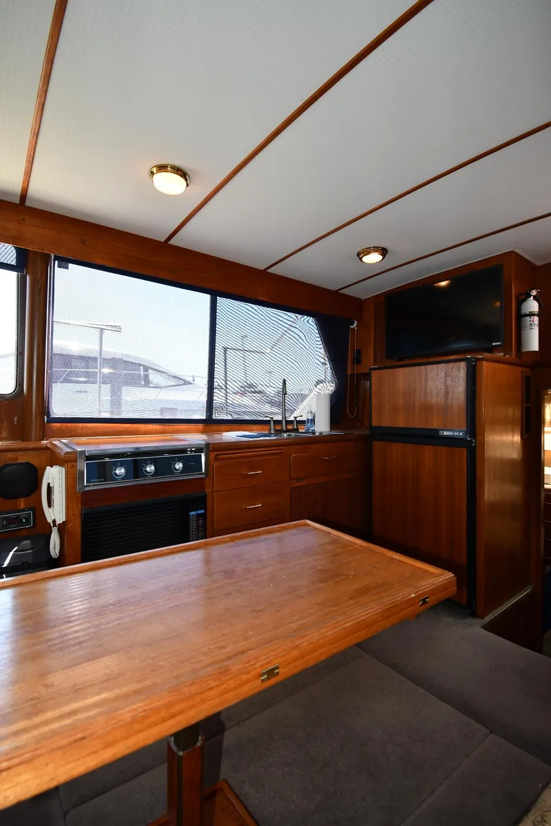 Slide: The Image of 1988 Tollycraft 34 Sundeck interior with wooden table, kitchenette, and seating area. - 43