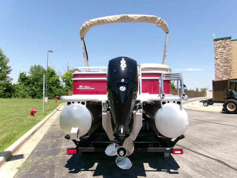 Slide: The Image of 2024 Sun Tracker Party Barge 22 RF XP3 pontoon boat with outboard motor, parked outdoors. - 2