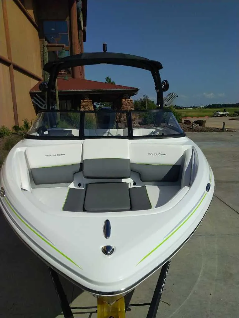 Slide: The Image of 2024 Tahoe 210 S boat docked near a building on a sunny day. - 1