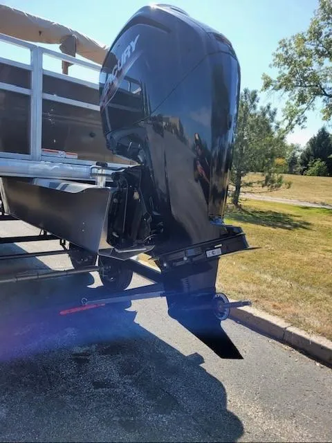 Slide: The Image of 2024 Sun Tracker SportFish 20 DLX with Mercury outboard engine, parked on a sunny day. - 2