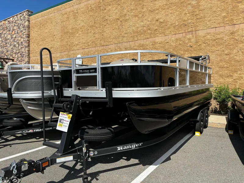 Slide: The Image of 2024 Ranger Reata 200F pontoon boat on a trailer in a parking lot. - 0