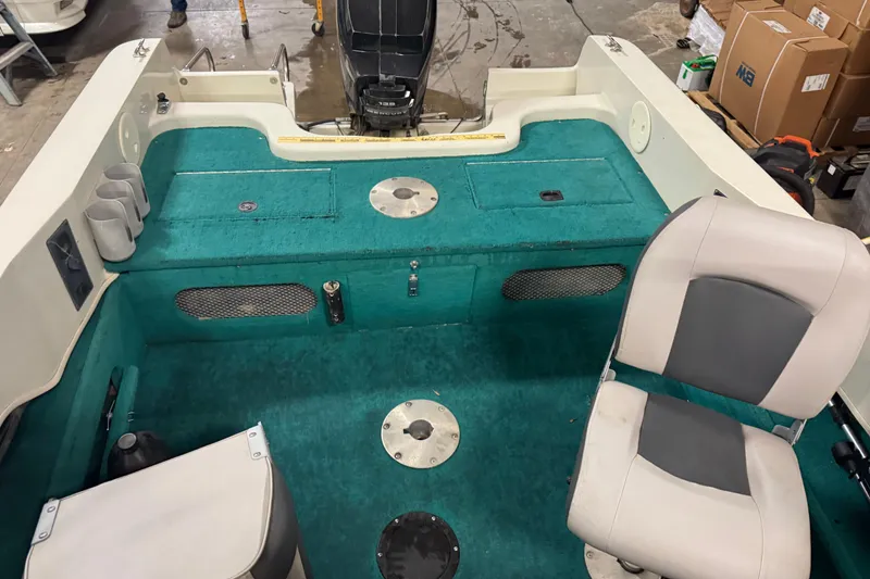 Slide: The Image of 1996 Sylvan VIPER boat interior with teal carpet and seating, featuring storage compartments. - 19