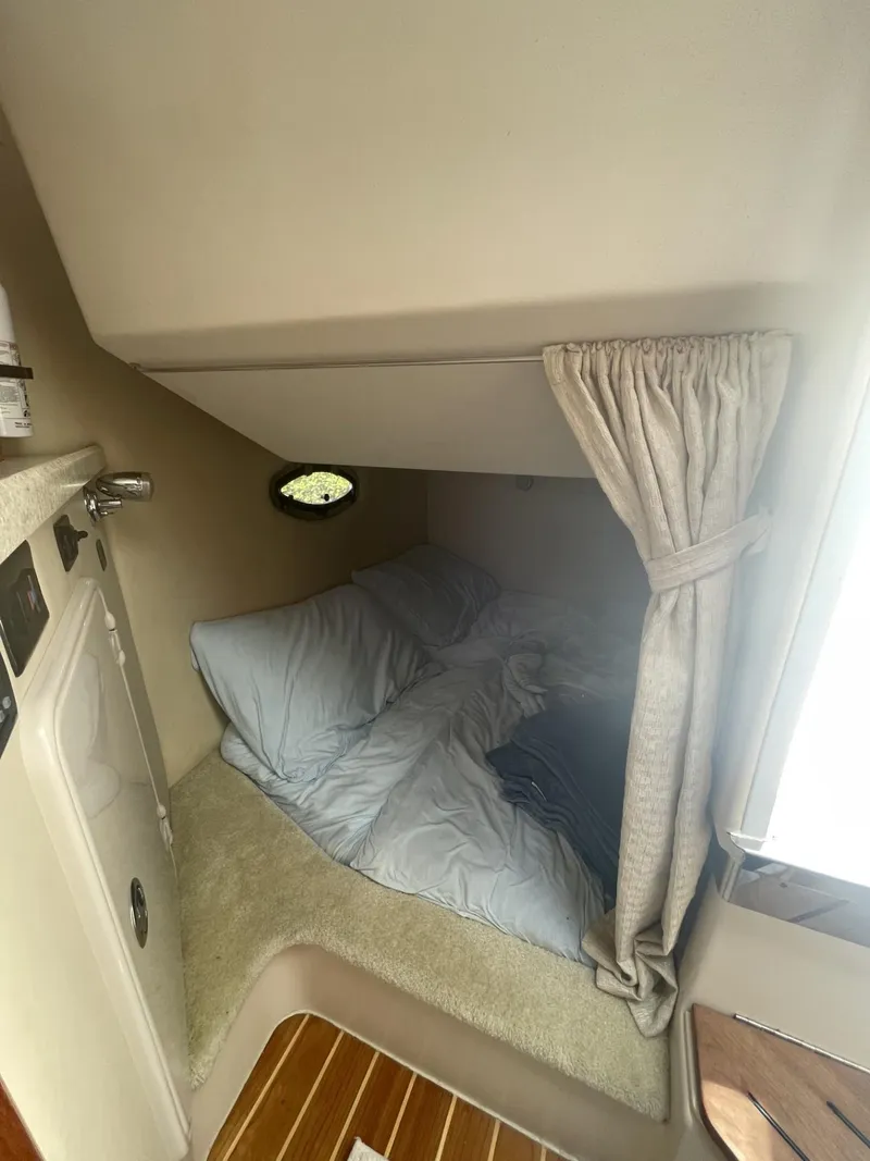 Slide: The Image of 2009 Regal 2565 Window Express cabin interior with cozy bedding and porthole. - 10