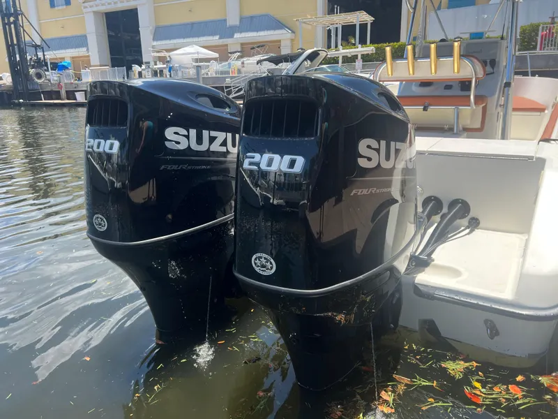 Slide: The Image of Twin Suzuki 200 outboard motors on a 1996 Pursuit 2470 CC boat docked in water. - 11