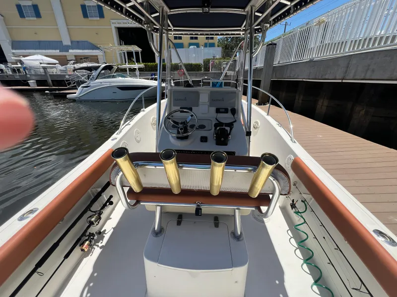 Slide: The Image of 1996 Pursuit 2470 CC boat docked, featuring helm station and rod holders. - 16