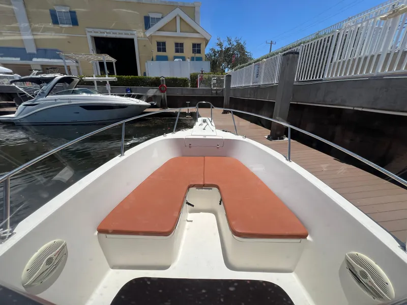 Slide: The Image of 1996 Pursuit 2470 CC boat docked at a marina with cushioned seating. - 23